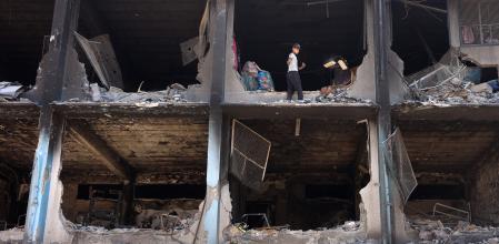 Un niño palestino rescata algunas pertenencias en una devastada escuela de la ONU  en el campo de refugiados de Yabalia, al norte de Gaza