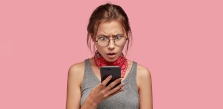 Una chica reaccionando sorprendida a su teléfono 