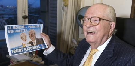 France's far-right Front National (FN) party founder Jean-Marie Le Pen holds a campaign poster in which he poses with his granddaughter Marion Marechal-Le Pen, now a French Member of Parliament for the FN, in Saint-Cloud, west of Paris, on January 27, 2016. (Photo by JOEL SAGET / AFP)