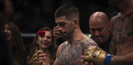 UFC featherweight champion Ilia Topuria, holds a rose presented to him by his wife after winning the featherweight title mixed martial arts bout against No. 2 ranked Max Holloway at UFC Fight Night on Saturday, Oct. 26, 2024, in Abu Dhabi, United Arab Emirates. Topuria won the fight. (AP Photo/Altaf Qadri)
