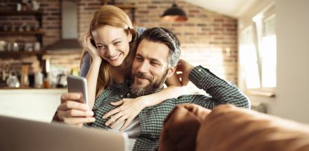 Una pareja en casa mirando el móvil