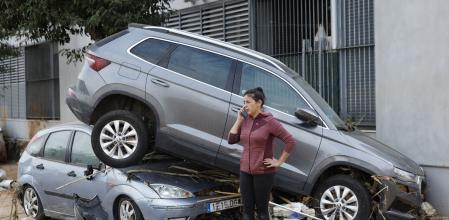 Una vecina habla por teléfono junto a dos coches destrozados, en Paiporta, Valencia, tras el paso de la DANA . EFE/ Biel Aliño