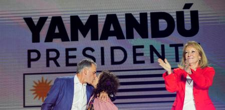 Uruguay's centre-left presidential candidate Yamandu Orsi kisses his wife Laura Alonso Perez onstage as running mate Carolina Cosse reacts, following early results of the presidential election run-off between Orsi and the candidate of the ruling conservative coalition Alvaro Delgado, in Montevideo, Uruguay November 24, 2024. REUTERS/Mariana Greif REFILE - REMOVING 