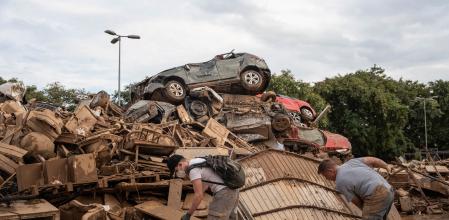 Dos personas realizan labores de limpieza al lado de una montaña de basura, vehículos y mobiliario destrozado tras el paso de la DANA en Alfafar, València