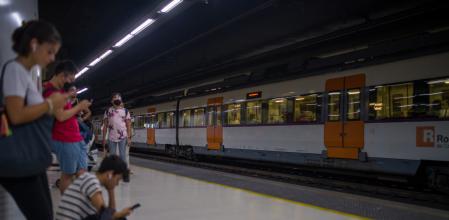 Viajeros esperan la llegada de un tren en uno de los andenes de la estación de Sants, en Barcelona 