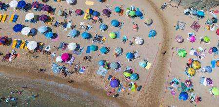 Numerosas personas disfrutan de un día de playa en la Costa Brava, a 30 de julio de 2023, en Tossa de Mar, Girona, Cataluña (España). Las playas españolas se llenan  de turistas para paliar el calor. De acuerdo con la información de la Agencia Estatal de Meteorología, los veranos en España se han ido calentando desde los años 80, con olas de calor cada vez más comunes e intensas. Los veranos son cada vez más largos, durando cinco semanas más y aumentando a un ritmo de nueve días por década.