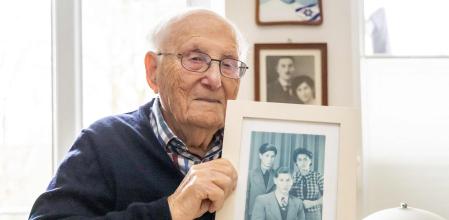 (FILES) The 99-year-old Holocaust survivor Albrecht Weinberg poses with a photo of (L-R) him, his brother Diedrich and his sister Friedel at his home in Leer (East Frisia), Germany, on December 30, 2024. Albrecht Weinberg survived the concentration camps of Auschwitz, Dora-Mittelbau and Bergen-Belsen, emigrated to the USA and returned to his homeland of East Frisia after decades as a shopkeeper in New York. (Photo by FOCKE STRANGMANN / AFP)