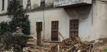 Un militar en las inmediaciones del lugar donde han hallado un cadáver en avanzado estado de descomposición, víctima de la DANA, a 12 de diciembre de 2024, en Paiporta, Valencia, Comunidad Valenciana (España). Efectivos de la Unidad Militar de Emergencias (UME) han localizado el cadáver de un varón en avanzado estado de descomposición en la zona ajardinada de la conocida Casa Gris de Paiporta, un edificio emblemático de la localidad situado en la calle València y punto neurálgico de los trabajos de reconstrucción del municipio.  El hallazgo de este nuevo cadáver, baja la cifra de desaparecidos por la DANA a tres personas.