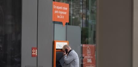 Un hombre saca dinero de un cajero automático del banco ING