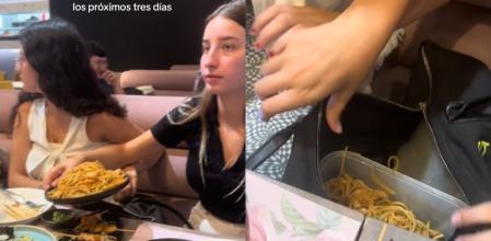 Una joven guarda un plato entero de un bufet libre en un táper que lleva dentro de su bolso