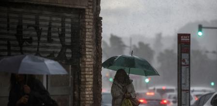 Dos mujeres caminan mientras se protegen de la lluvia con paraguas en foto de archivo&nbsp;