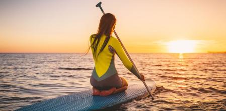 Una chica navega en una tabla de paddlesurf mientras disfruta del atardecer