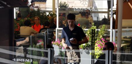 Un camarero cobrando a dos clientes en una terraza en Vielha