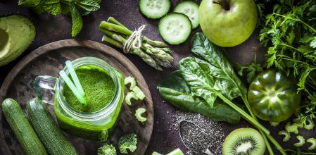 Vista desde arriba de una mesa rústica llena de frutas y verduras verdes