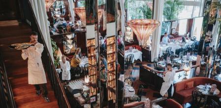 Un camarero baja del comedor de la primera planta al principal, con la cristalera que da al jardín