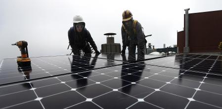 SAN FRANCISCO, CA - MAY 09: Luminalt solar installers Pam Quan (L) and Walter Morales (R) install solar panels on the roof of a home on May 9, 2018 in San Francisco, California. The California Energy Commission is set to vote on proposed legislation that would require all new homes in the state of California to have solor panels. If passed, the new mandate would require the panels on new homes up to three stories tall and is estimated to cost nearly $10K per home. Justin Sullivan/Getty Images/AFP == FOR NEWSPAPERS, INTERNET, TELCOS & TELEVISION USE ONLY ==