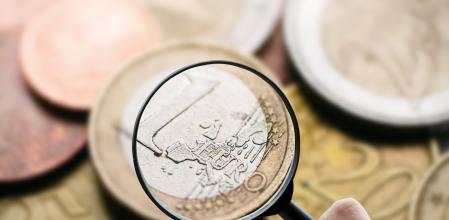 Un usuario inspeccionando con lupa una moneda de un euro