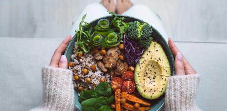 Alimentación saludable. Plato con comida vegana o vegetariana en manos de mujer.