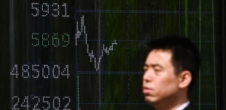 Un hombre camina en Beijing con un marcador del índice de la bolsa de fondo.&nbsp;