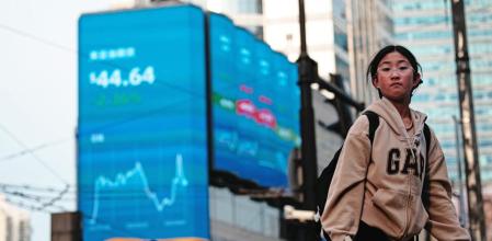Shanghai (China), 07/04/2025.- People walk on a street near screens showing stock exchange and economic data in Shanghai, China, 07 April 2025. Hong Kong and Chinese stocks plummeted dramatically on April 7 after Beijing countered US tariffs with its own set of trade levies. The move sent shock waves through financial markets, igniting fears among investors of an expanding trade war that could plunge the global economy into a severe recession. EFE/EPA/ALEX PLAVEVSKI