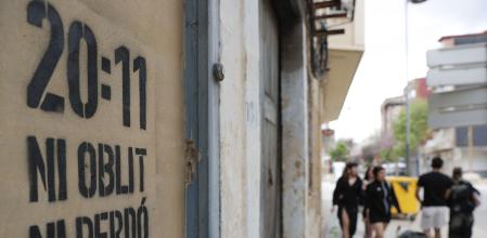 En la imagen varias personas pasan ante un pintada realizada en una casa afectada por la dana en Catarroja, que recuerda la hora a la que se envió el mensaje de alerta y el lema “Ni oblit, ni perdó”&nbsp;