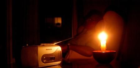 Un jubilado escucha la radio a la luz de las velas, al haberse quedado sin luz por un apagón eléctrico