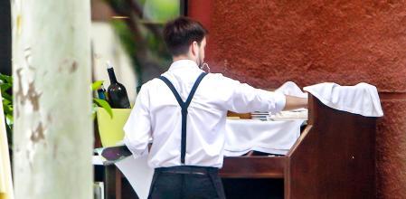 Un camarero atiende a los clientes de una terraza en una sidrería de Madrid.