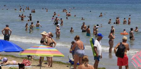 Personas se refrescan en la playa de Alicante cuando el calor de las últimas semanas ha disparado hasta alrededor de los 25 grados la temperatura del Mediterráneo