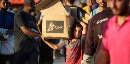 Un niño llevando una caja con ayuda entregada por GHF cerca de Nuseirat, esta semana