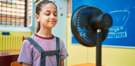 Una niña se refresca con un mini ventilador