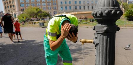 Un empleado del servicio de limpieza viaria se refresca en una fuente en el centro de Barcelona&nbsp;