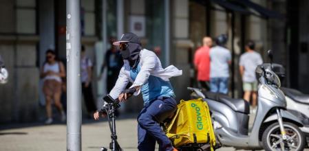 Un repartidor de comida a domicilio se protege frente a la radiación solar hace unos días en Barcelona