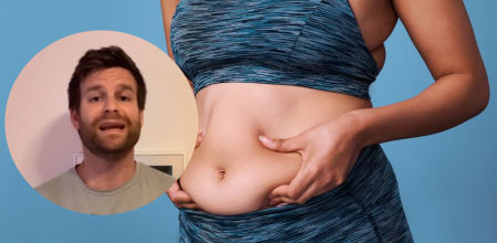 Una mujer sujetando su grasa abdominal