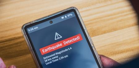 Un hombre sujeta su móvil mientras aparece una alerta de terremoto.