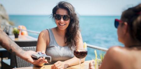 Mujer paga la cuenta con su tarjeta en un restaurante al lado del mar