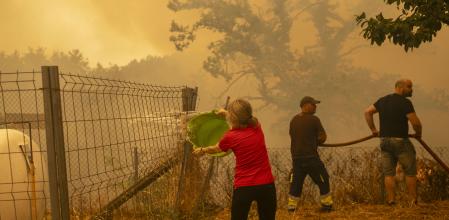 Vecinos de la aldea deLamas, intentando aplacar el fuego ayer con cubos de agua y mangueras