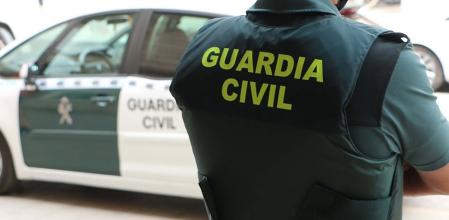Archivo - Un agente de la Guardia Civil, de espaldas, junto a un vehículo oficial.
