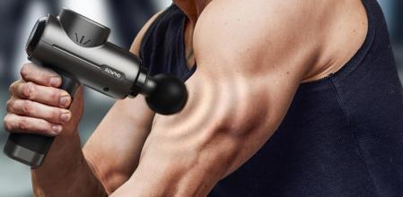 Un deportista utilizando la pistola para darse un masaje en los brazos