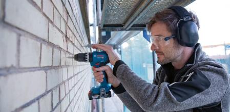 Un hombre taladrando una pared de ladrillos