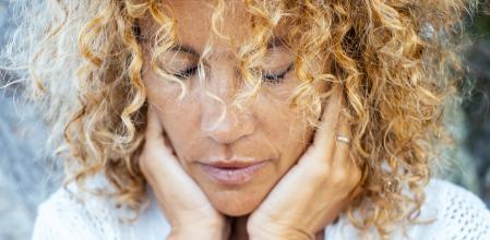 Introspection and meditation concept lifestyle with one woman alone close up portrait touching softly her face with both hands having care. Thoughts and difficulty concept life moments. Female people