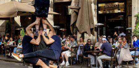 Unos turistas se distraen con un espectáculo callejero este verano en el centro de Barcelona