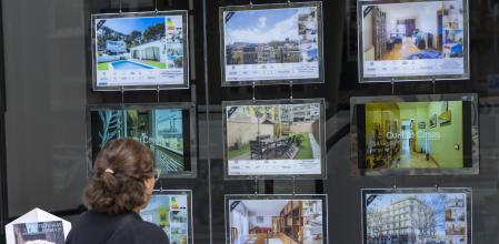 Una mujer observa el escaparate de una inmobiliaria, en la ciudad de Barcelona