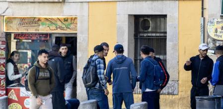 Un joven con sudadera verde, camina junto algunos de los vendedores habituales de medicamentos de la Rambla del Raval