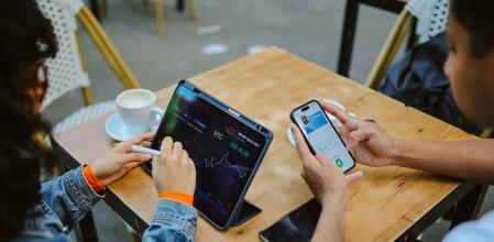 Jóvenes consultando cotizaciones de criptomonedas en dispositivos electrónicos