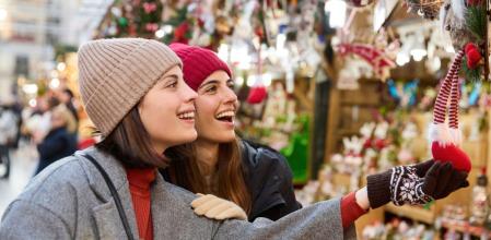 Una pareja de amigas visitando un mercadillo navideño durante el puente de diciembre