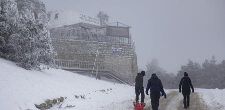 Varias personas arrastran un trineo en el Puerto de Navacerrada, en Madrid,.