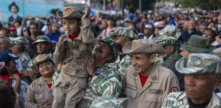 Un integrant de la Milícia Nacional Bolivariana de Veneçuela carrega una nena durant una manifestació pel 26 aniversari de la Constitució de Veneçuela a Caracas.