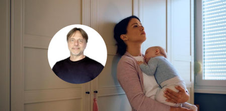 Una madre sosteniendo a su bebé dormido en sus brazos en casa