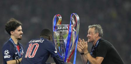 PSG's head coach Luis Enrique and players Vitinha, left, and Ousmane Dembele look at the trophy at the end of the Champions League final soccer match between Paris Saint-Germain and Inter Milan at the Allianz Arena in Munich, Germany, Saturday, May 31, 2025. (AP Photo/Luca Bruno)