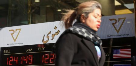 Una mujer pasa junto a un cartel en una casa de cambio de Teherán, mientras el valor del rial iraní cae&nbsp;